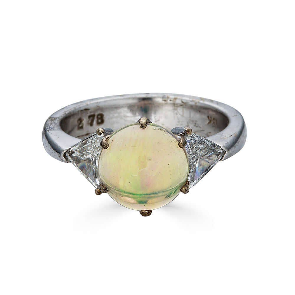 Antique Opal and Trillion Cut Diamond RingDiscover an incredible opal find with this stunning 18k white gold three-stone ring! Featuring a mesmerizing, almost 10mm opal cabochon as its center stone, this ring is a future heirloom in the making. The opal i