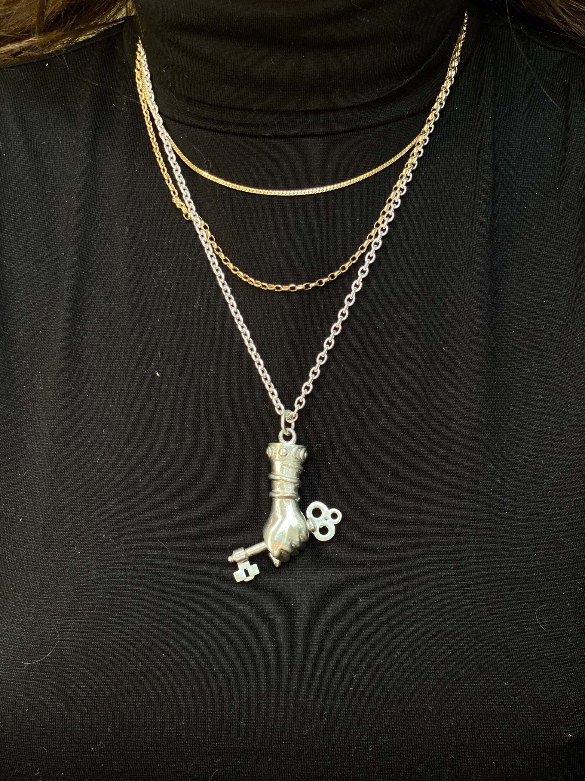 Hekate Dexia - The KeyBased on the traditional Figa the Mano Fico, this pendant is intended to be a symbol to ward of evil and protect the wearer. The inspiration behind it was Hekate, the greek god of witchcraft, the moon, and femininity. In her hands sh