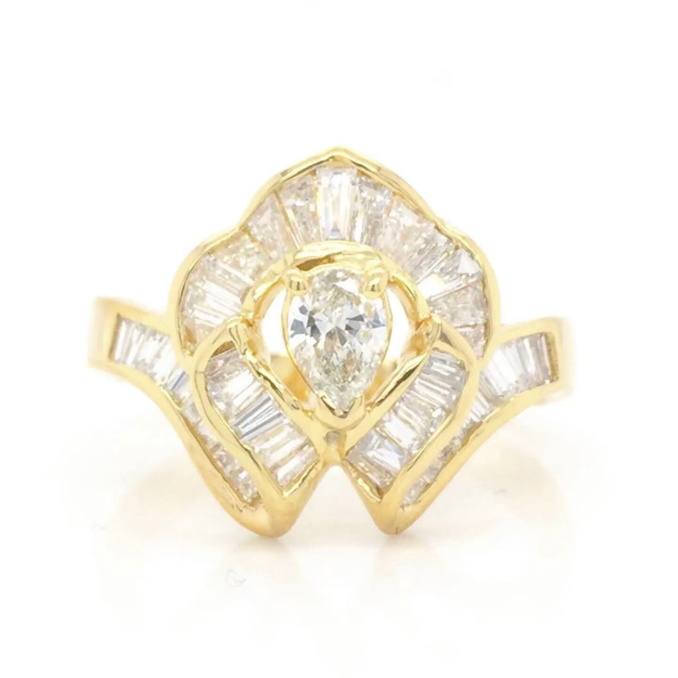 Vintage 18k Ballerina Ring with Pear-Shaped Diamond and Baguette MeleeA vintage diamond ring beautifully crafted in 18k gold with a central pear shaped diamond and a lovely arrangement of baguette diamonds that glisten in all sorts of light and will sure