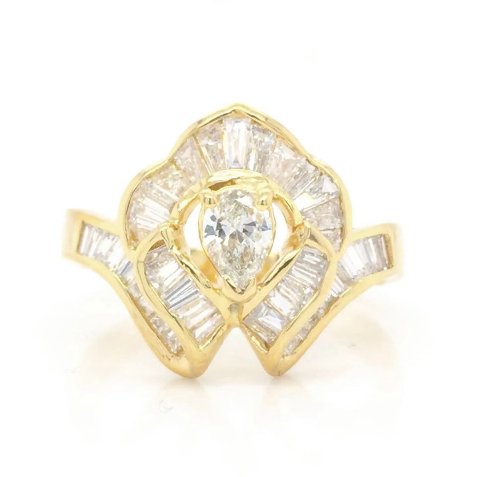 Vintage 18k Ballerina Ring with Pear-Shaped Diamond and Baguette MeleeA vintage diamond ring beautifully crafted in 18k gold with a central pear shaped diamond and a lovely arrangement of baguette diamonds that glisten in all sorts of light and will sure