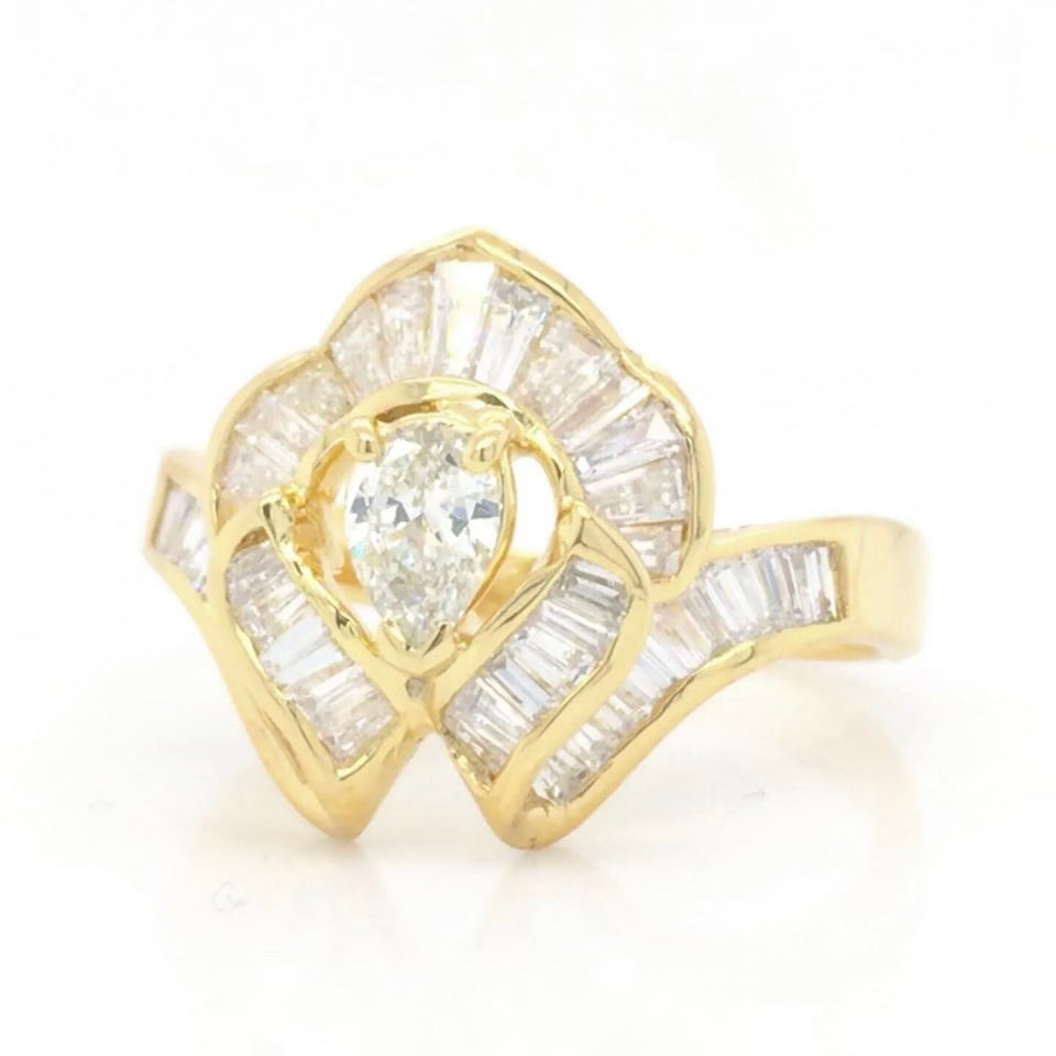 Vintage 18k Ballerina Ring with Pear-Shaped Diamond and Baguette MeleeA vintage diamond ring beautifully crafted in 18k gold with a central pear shaped diamond and a lovely arrangement of baguette diamonds that glisten in all sorts of light and will sure