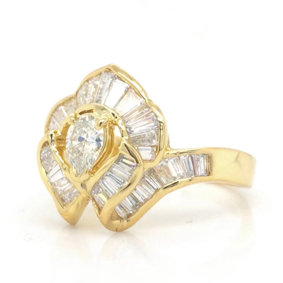 Vintage 18k Ballerina Ring with Pear-Shaped Diamond and Baguette MeleeA vintage diamond ring beautifully crafted in 18k gold with a central pear shaped diamond and a lovely arrangement of baguette diamonds that glisten in all sorts of light and will sure