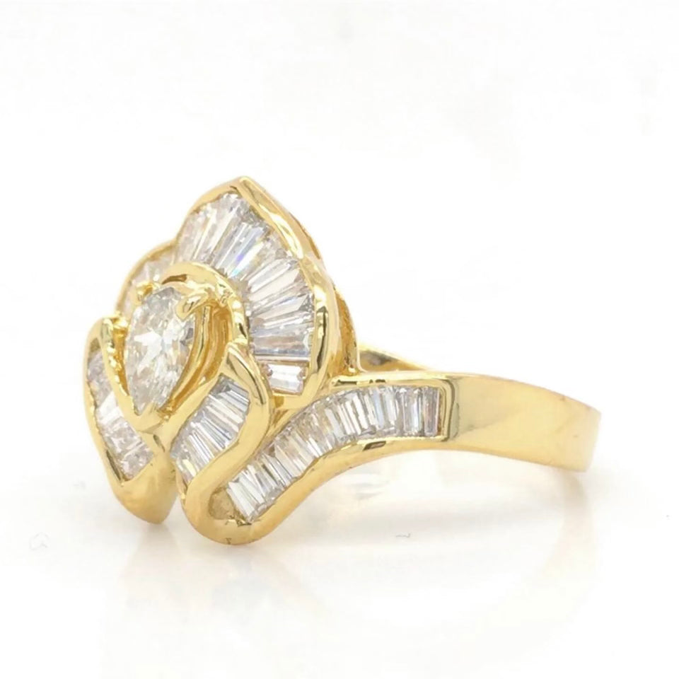 Vintage 18k Ballerina Ring with Pear-Shaped Diamond and Baguette MeleeA vintage diamond ring beautifully crafted in 18k gold with a central pear shaped diamond and a lovely arrangement of baguette diamonds that glisten in all sorts of light and will sure