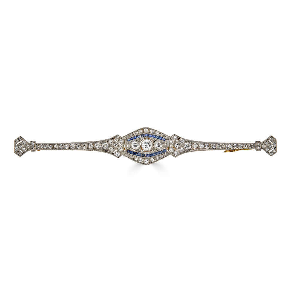 Elongated Art Deco Platinum Brooch with Diamonds and Calibrated SapphiresA beautiful and elongated brooch that will certain draw the right amount of attention to your ensemble. This brooch ticks everything we love; sparkly diamonds, unique shape, and the