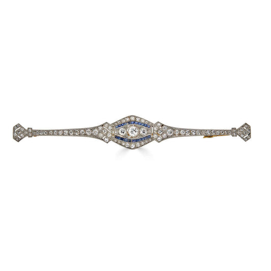 Elongated Art Deco Platinum Brooch with Diamonds and Calibrated SapphiresA beautiful and elongated brooch that will certain draw the right amount of attention to your ensemble. This brooch ticks everything we love; sparkly diamonds, unique shape, and the